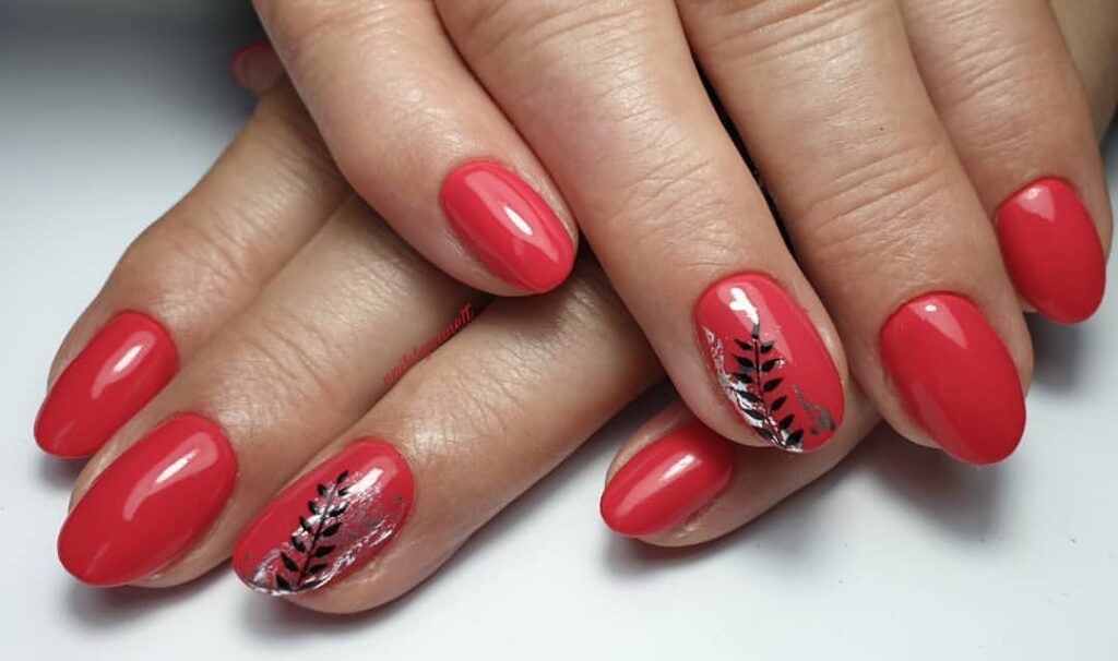 Round red nails with black leaf designs.